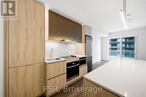 Toronto (Niagara) condo for rent - A modern kitchen with wooden cabinets and a white countertop.