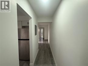 Windsor apartment for rent - A long hallway with a refrigerator on the left and a door at the end.