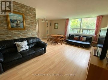 Markham (Thornhill) condo for rent - A living room with a black couch and a stone wall.