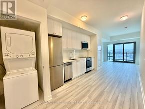 Clarington (Bowmanville) condo for rent - A well-lit kitchen with white appliances and wooden flooring.