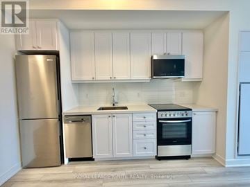 Clarington (Bowmanville) condo for rent - A kitchen with white cabinets and appliances.
