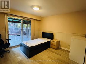 Toronto (Highland Creek) apartment for rent - A bedroom with a bed, chair, and a window with a view of a patio.