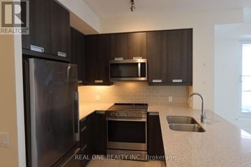 Mississauga (Hurontario) condo for rent - A modern kitchen with dark brown cabinets and stainless steel appliances.