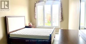 Markham (Berczy) apartment for rent - A bedroom with a bed, a table, and a window.