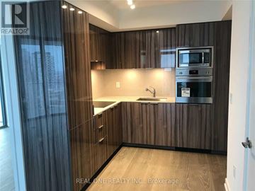 Toronto (Bay Street Corridor) condo for rent - A modern kitchen with wooden cabinets and a stainless steel oven.