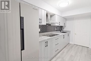 Ajax (Central East) apartment for rent - A kitchen with white cabinets and a black refrigerator.