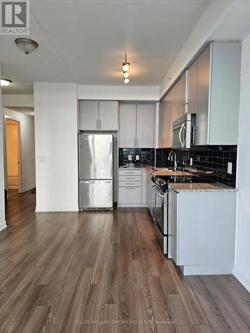 Toronto (Yonge-Eglinton) condo for rent - A kitchen with white cabinets and a black backsplash.