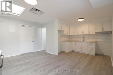 Toronto (Kensington-Chinatown) apartment for rent - A spacious kitchen with white cabinets and a wooden floor.