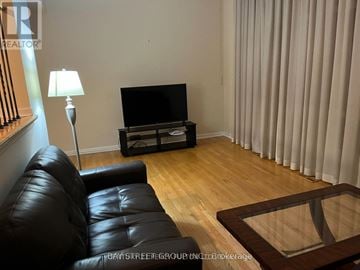 Toronto (Hillcrest Village) townhouse for rent - A black leather sofa sits in front of a television in a living room.