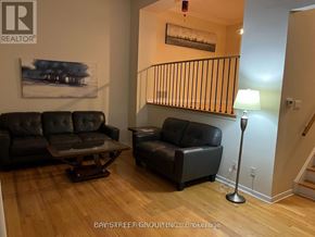 Toronto (Hillcrest Village) townhouse for rent - A living room with a black couch and a painting on the wall.