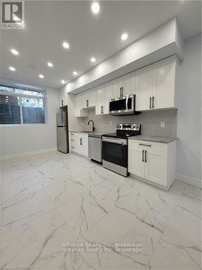 Tillsonburg multi-family for rent - A modern kitchen with white cabinets and appliances.