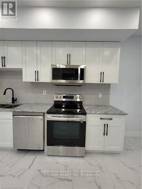 Tillsonburg multi-family for rent - A kitchen with white cabinets and a marble countertop.