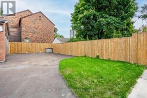 Toronto (Mount Dennis) apartment for rent - A backyard with a wooden fence and a driveway.