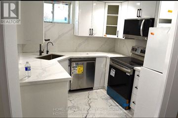 Hamilton (Waterdown) apartment for rent - A kitchen with white cabinets and a black fridge.
