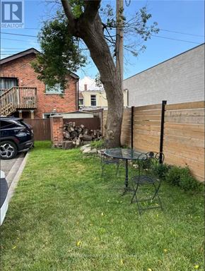 Hamilton (Dundas) apartment for rent - A backyard with a tree, a table and chairs, and a wooden fence.