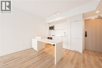 Burlington condo for rent - A white kitchen with wooden floors and a white cabinet with a microwave and oven.
