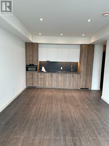 Kitchener condo for rent - A spacious kitchen with wooden cabinets and a black countertop.