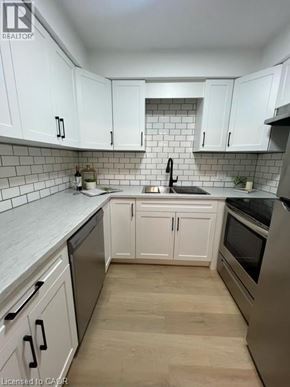 Kitchener apartment for rent - A kitchen with white cabinets and a black stove top oven.