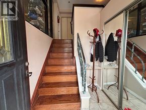 Windsor apartment for rent - A wooden staircase with a black door on the left and a coat rack with two coats hanging on it.