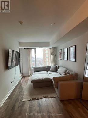 Ottawa condo for rent - A living room with a couch, a rug, and a large window.