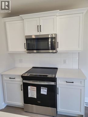 Plympton-Wyoming apartment for rent - A kitchen with white cabinets and a stainless steel microwave above the stove.