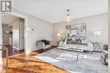 Oshawa (Donevan) apartment for rent - A living room with a white couch and a grey rug.