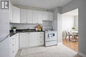 Toronto (Rockcliffe-Smythe) condo for rent - A kitchen with white cabinets and a black countertop.