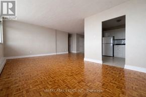 Toronto (Rockcliffe-Smythe) condo for rent - A room with wooden flooring and a kitchen area in the background.