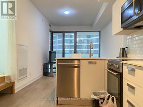 Toronto (Bay Street Corridor) condo for rent - A kitchen with a stainless steel dishwasher and oven, and a window with a view of a cityscape.