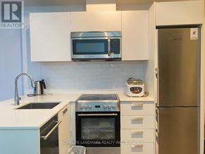 Toronto (Bay Street Corridor) condo for rent - A kitchen with a stainless steel refrigerator and white cabinets.