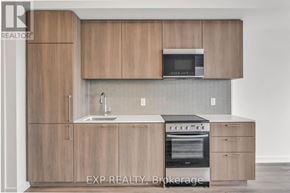 Toronto (Rouge) condo for rent - A kitchen with wooden cabinets and a microwave above the sink.