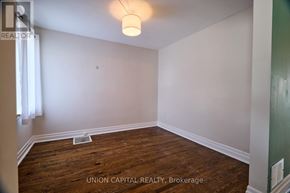 Oshawa (O'neill) apartment for rent - A room with wood flooring and white walls, with a light fixture hanging from the ceiling.