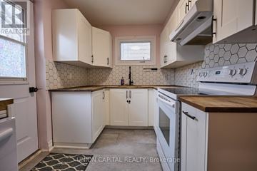 Oshawa (O'neill) apartment for rent - A kitchen with white cabinets and a black and white tile backsplash.