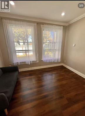 Richmond apartment for rent - A living room with a black couch and a window with white curtains.