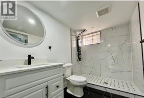 Hamilton apartment for rent - A white bathroom with a round mirror and a white toilet.