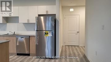 Guelph (Willow West/Sugarbush/West Acres) condo for rent - A kitchen with a stainless steel refrigerator and a door on the right.