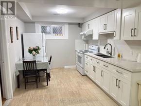 Toronto (Steeles) apartment for rent - A kitchen with white cabinets and a table set for two.