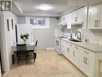 Toronto (Steeles) apartment for rent - A kitchen with white cabinets and a table set for two.