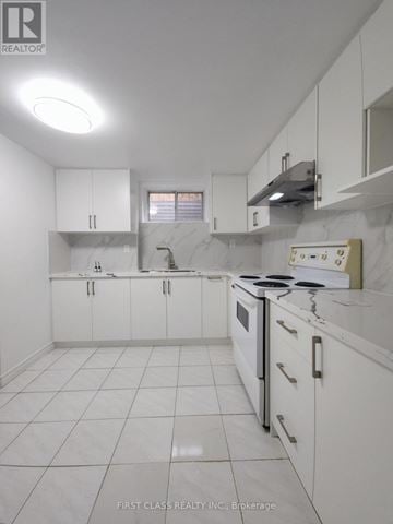 Toronto (Agincourt North) apartment for rent - A white kitchen with a stove top oven and a range hood.