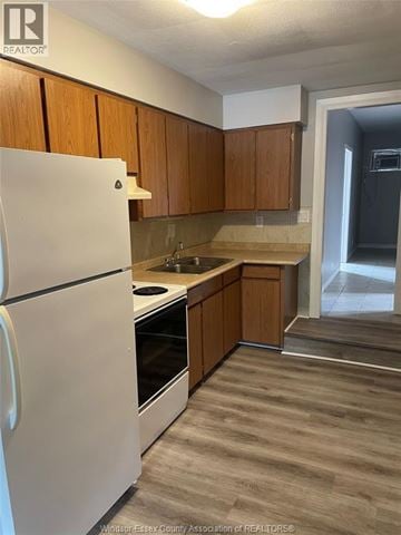 Tecumseh apartment for rent - A kitchen with a white refrigerator and wooden cabinets.
