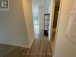 Toronto (Church-Yonge Corridor) condo for rent - A hallway with wood flooring and white walls, leading to a door with a black frame.