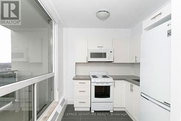 Toronto (University) condo for rent - A small white kitchen with a microwave and stove.