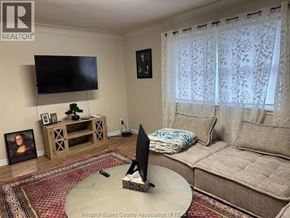 Windsor apartment for rent - A living room with a flat screen TV mounted on the wall above a wooden entertainment center.