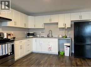 Windsor apartment for rent - A bedroom with a bed, a window with blue curtains, and a wooden dresser.