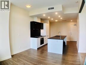 Burnaby apartment for rent - A modern kitchen with wooden floors and a black countertop.