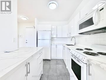 Toronto (University) condo for rent - A white kitchen with a stove top oven and a microwave above it.