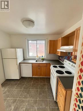 Toronto (Woodbine Corridor) triplex for rent - A kitchen with a white refrigerator, white stove, and wooden cabinets.