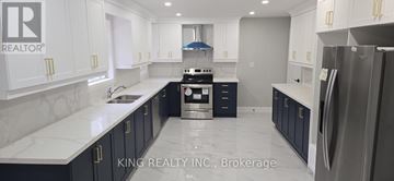 Brampton (Credit Valley) apartment for rent - A modern kitchen with a refrigerator on the right and cabinets in white and dark blue.