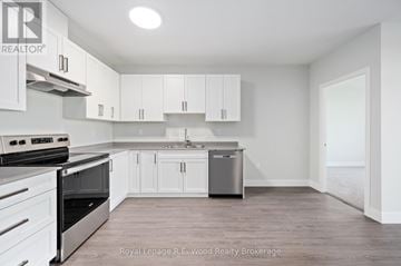 Tillsonburg multi-family for rent - A white kitchen with a stove top oven and a dishwasher.