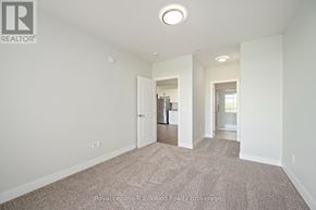 Tillsonburg multi-family for rent - A large, empty room with a carpeted floor and white walls.
